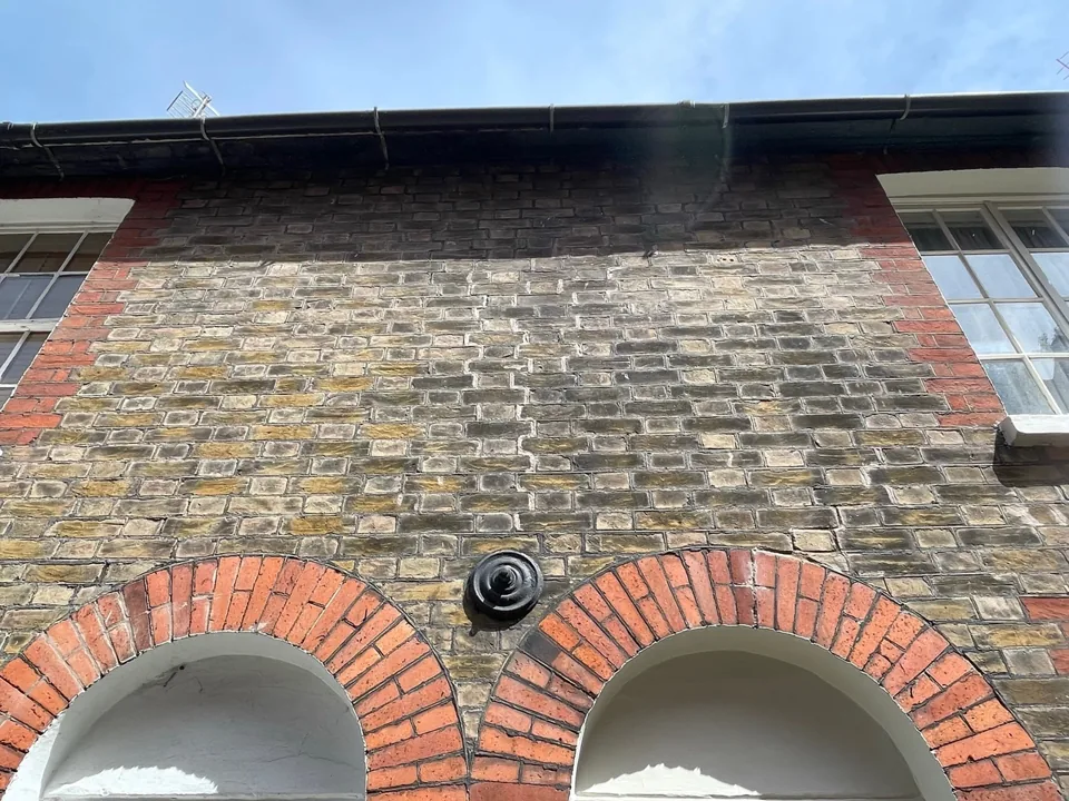 Flint wall with red-brick arches beneath the eaves.