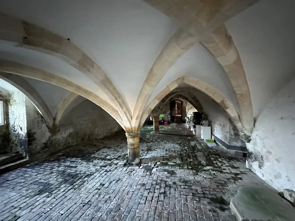Vaulted interior with stone supports and an exposed brick floor.