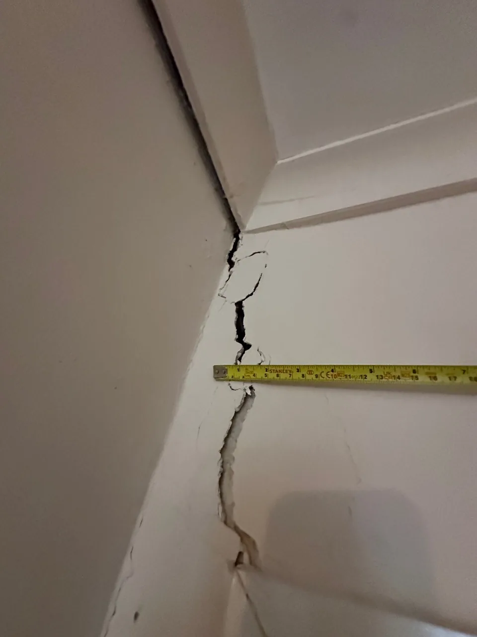 An internal wall crack shown alongside a tape measure.