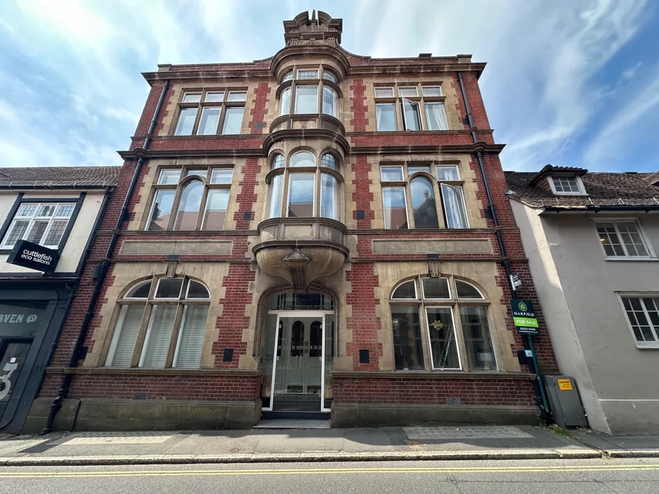 Tall period building with decorative brickwork, stone detailing and bay windows.