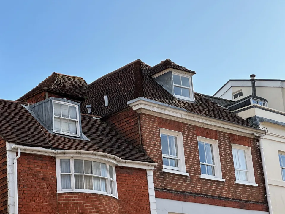Period house with dormer windows, a tiled roof and a projecting bay.