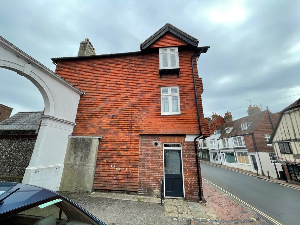 Red-brick street elevation with a projecting gable and tall windows.