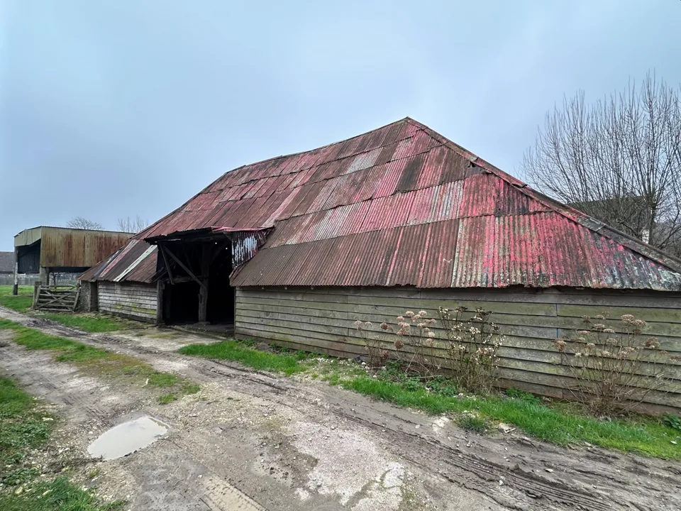 Timber-clad rural barn with a broad corrugated roof.