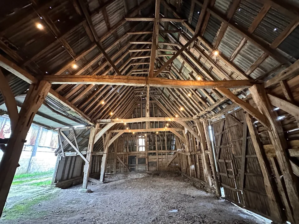 Barn interior with exposed timber framing, roof trusses and a gravel floor.