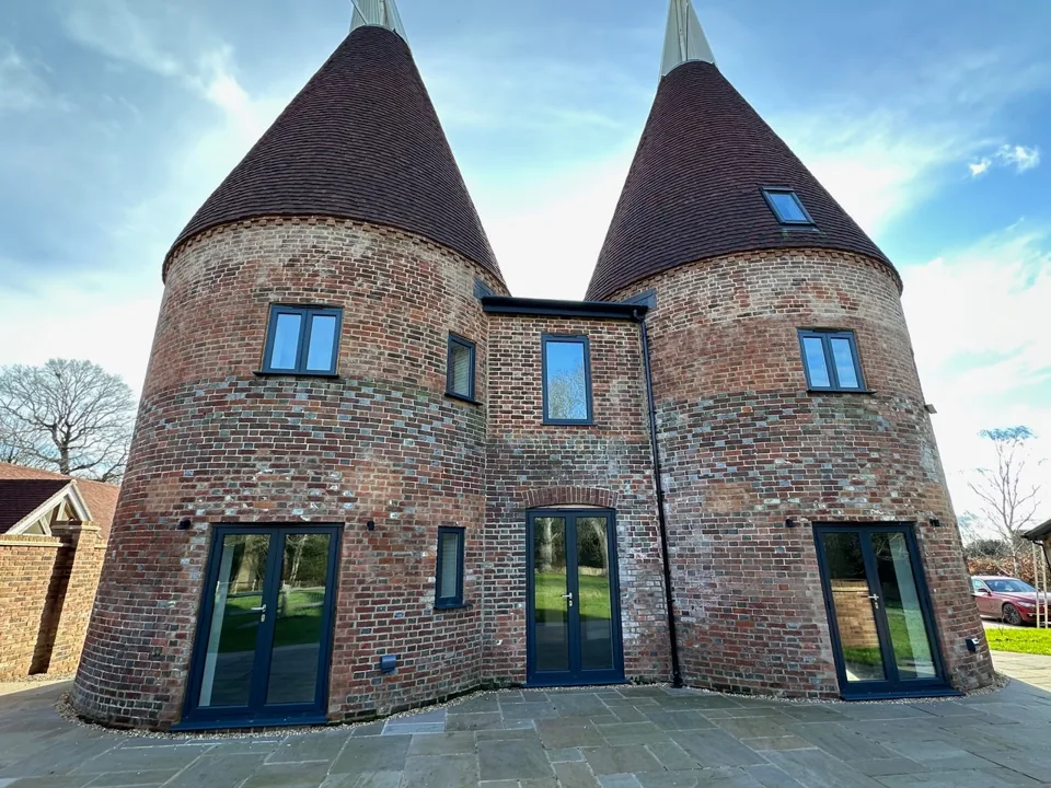 Brick property with two round towers and conical tiled roofs.